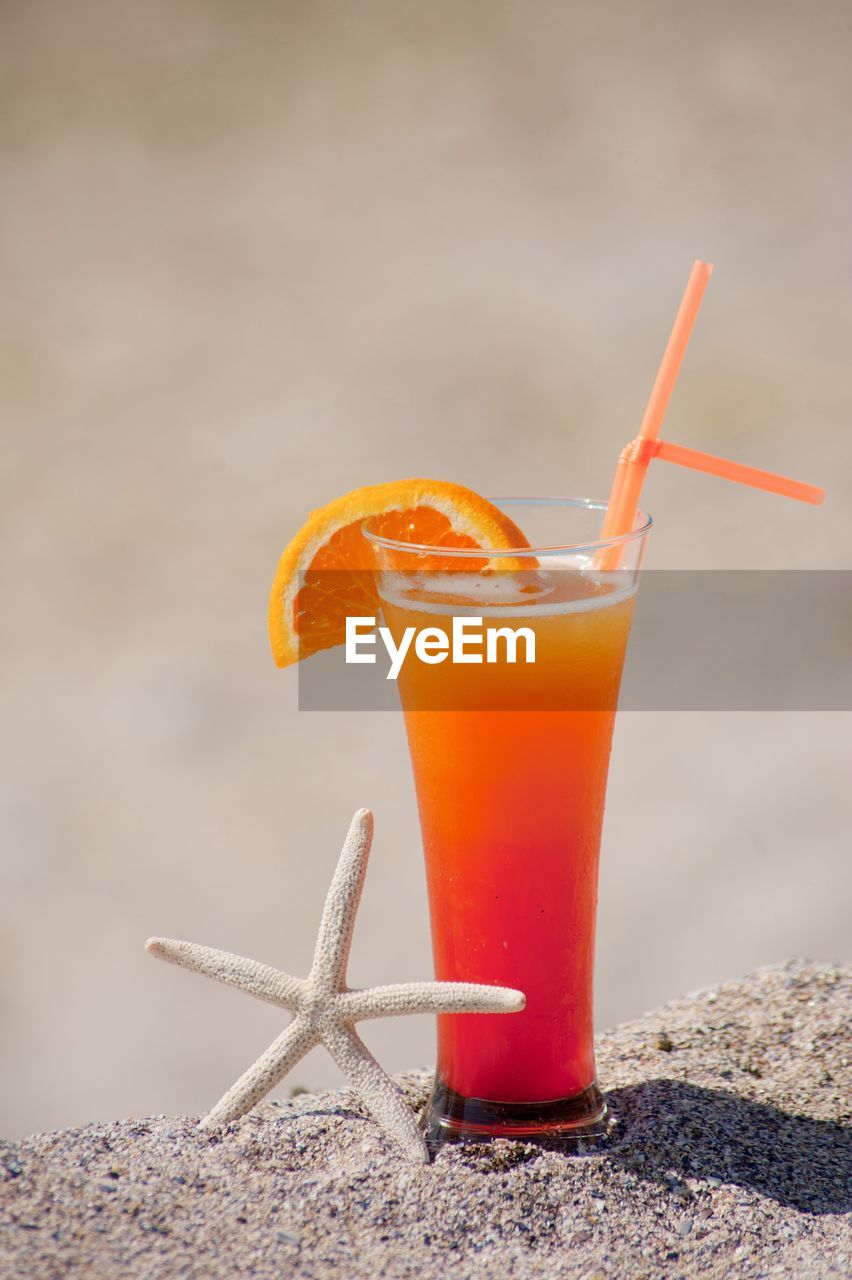 Close-up of orange juice on sand