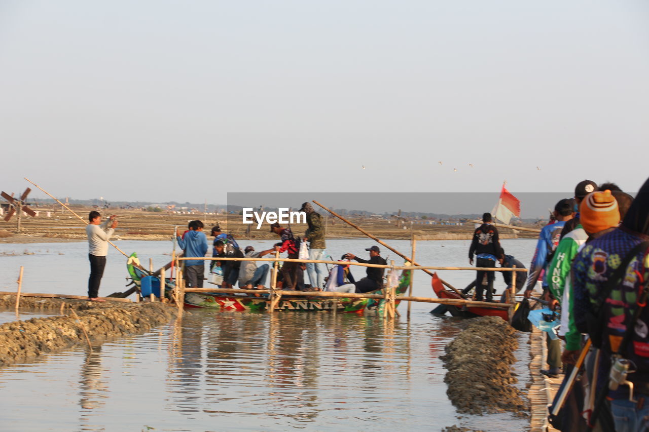 PEOPLE ON BOAT AGAINST SEA AGAINST CLEAR SKY