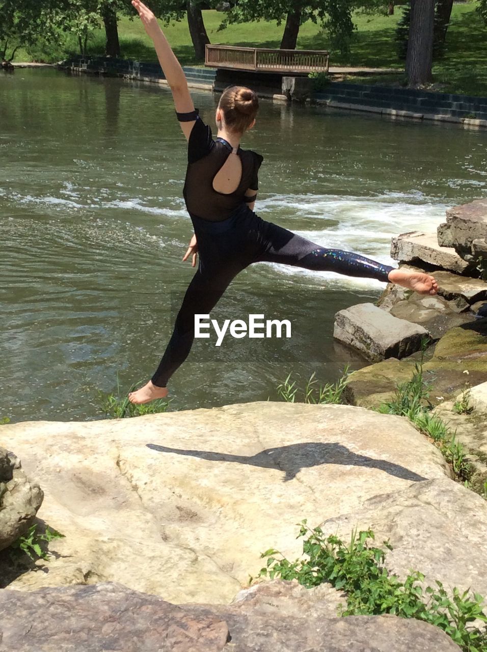 Full length rear view of ballerina dancing by lake in park