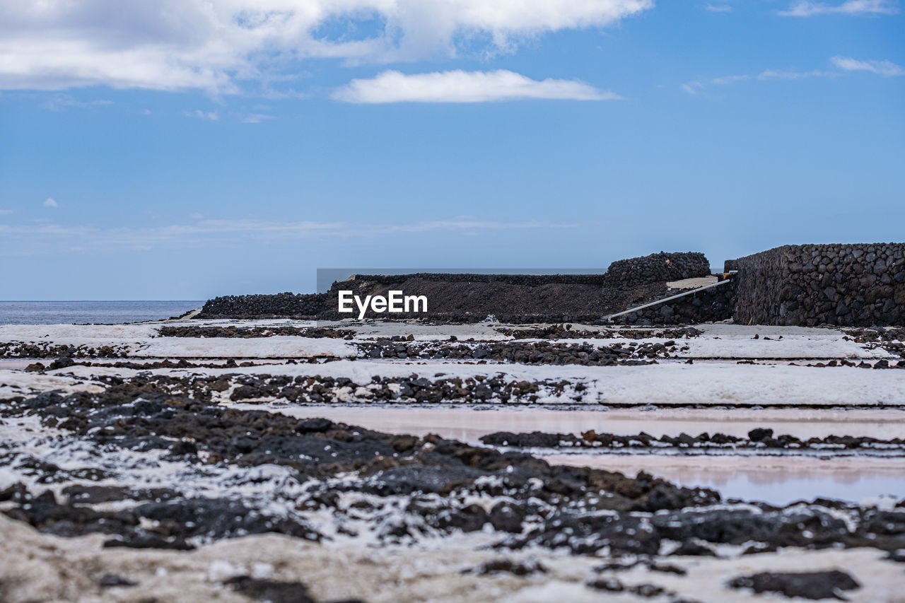 Surface level of salt pan against sky