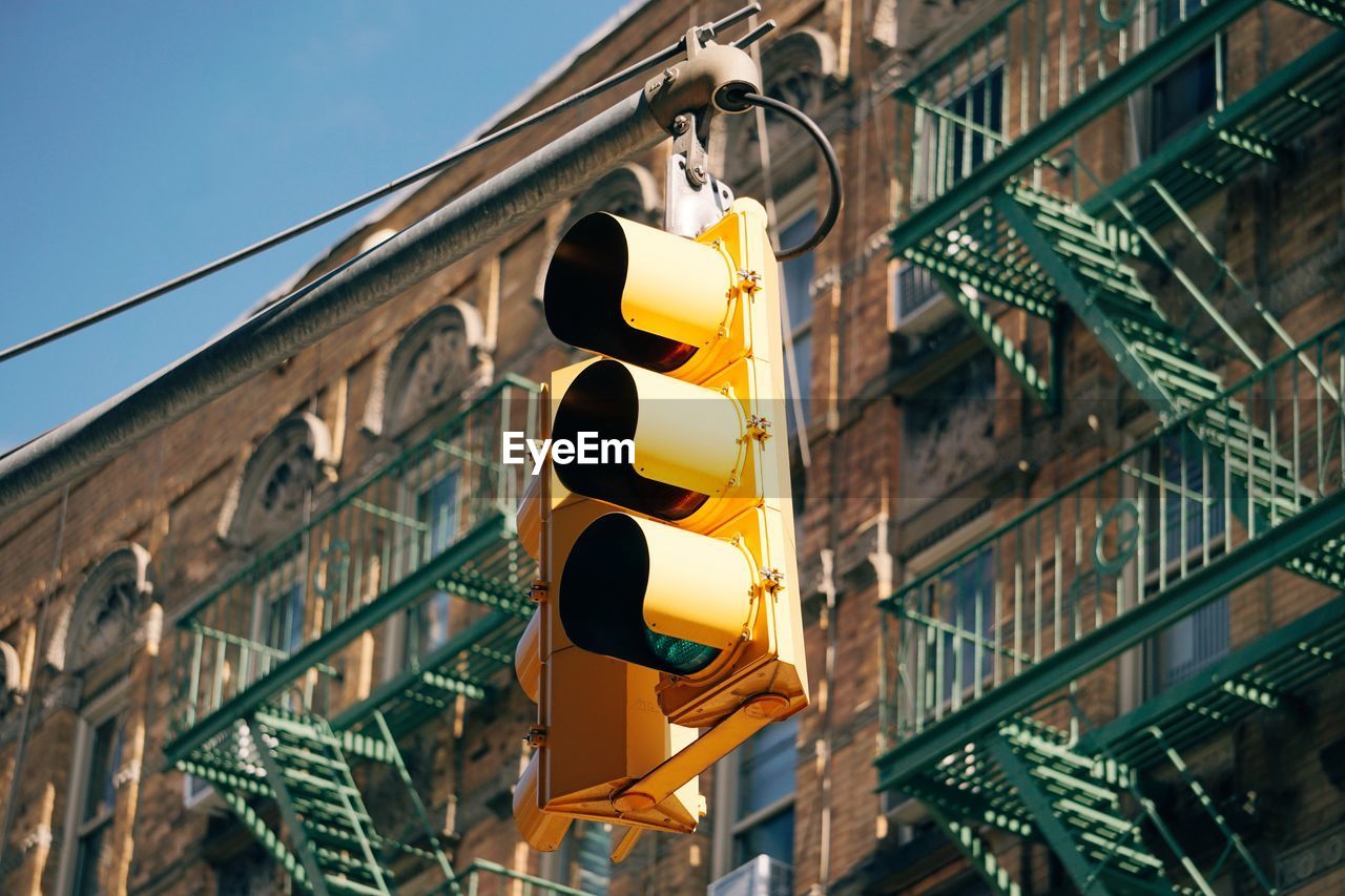 Low angle view of road signal against building in city during sunny day