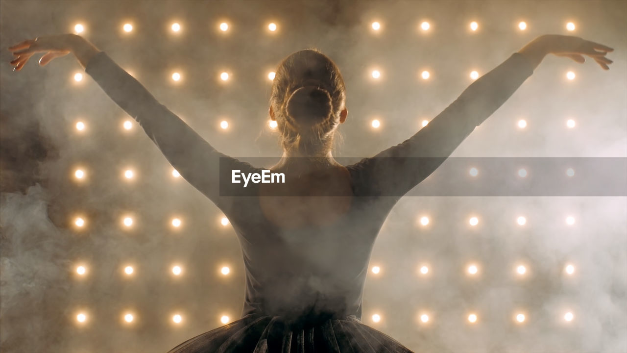 Ballerina dancing against illuminated lights