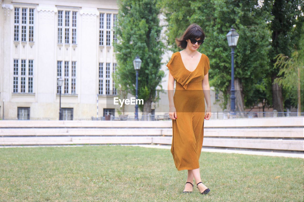 Young woman walking on lawn against building