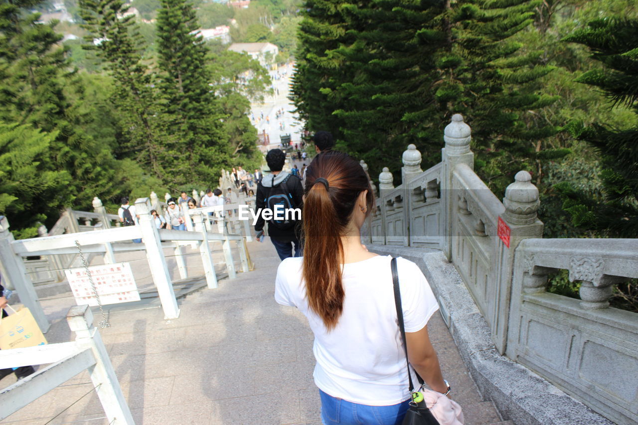 REAR VIEW OF WOMAN STANDING ON ROAD