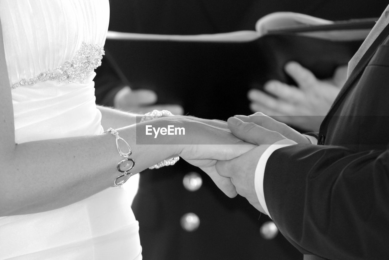 Midsection of bride and bridegroom taking wedding vows