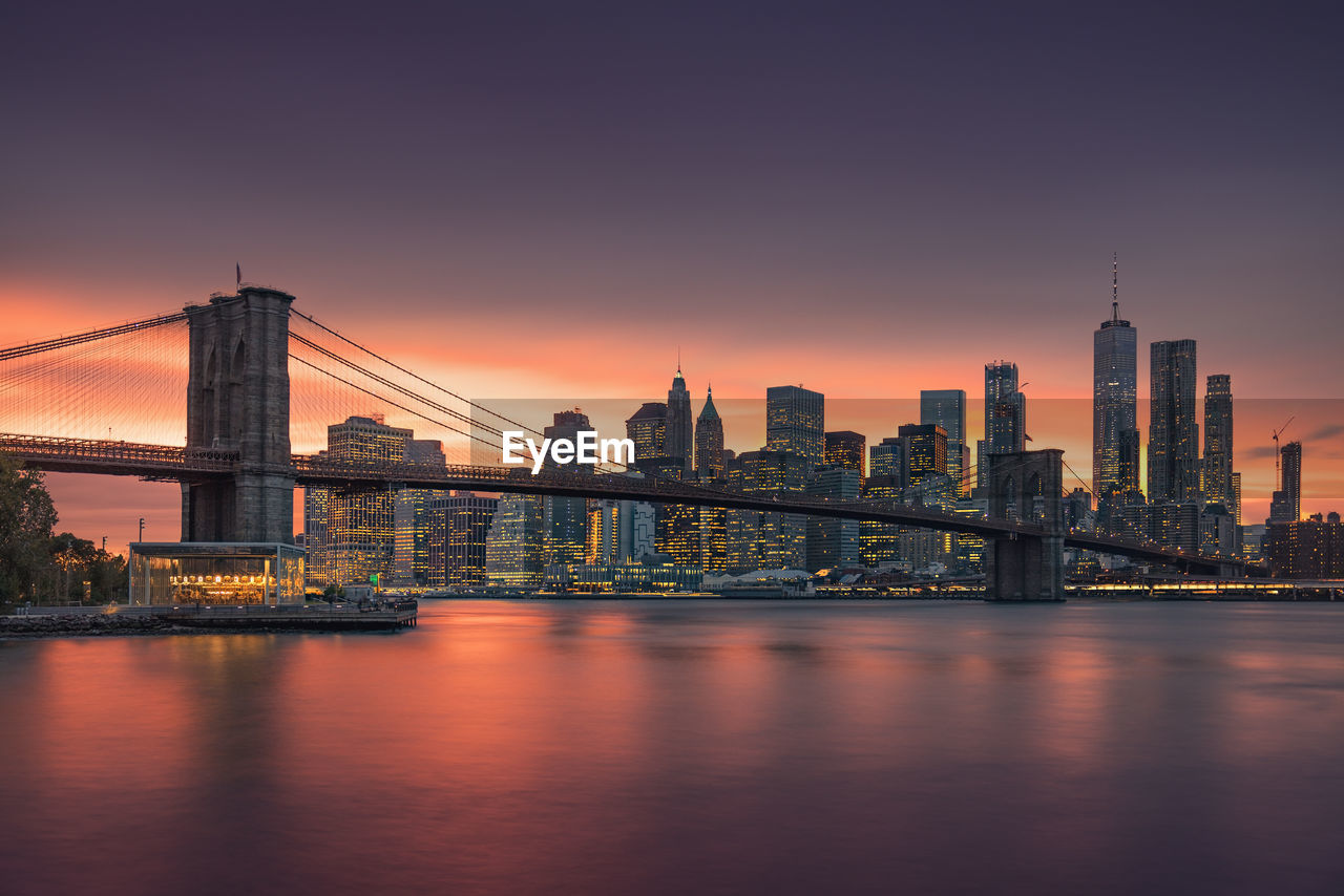 Brooklyn bridge over river with buildings in background during sunset