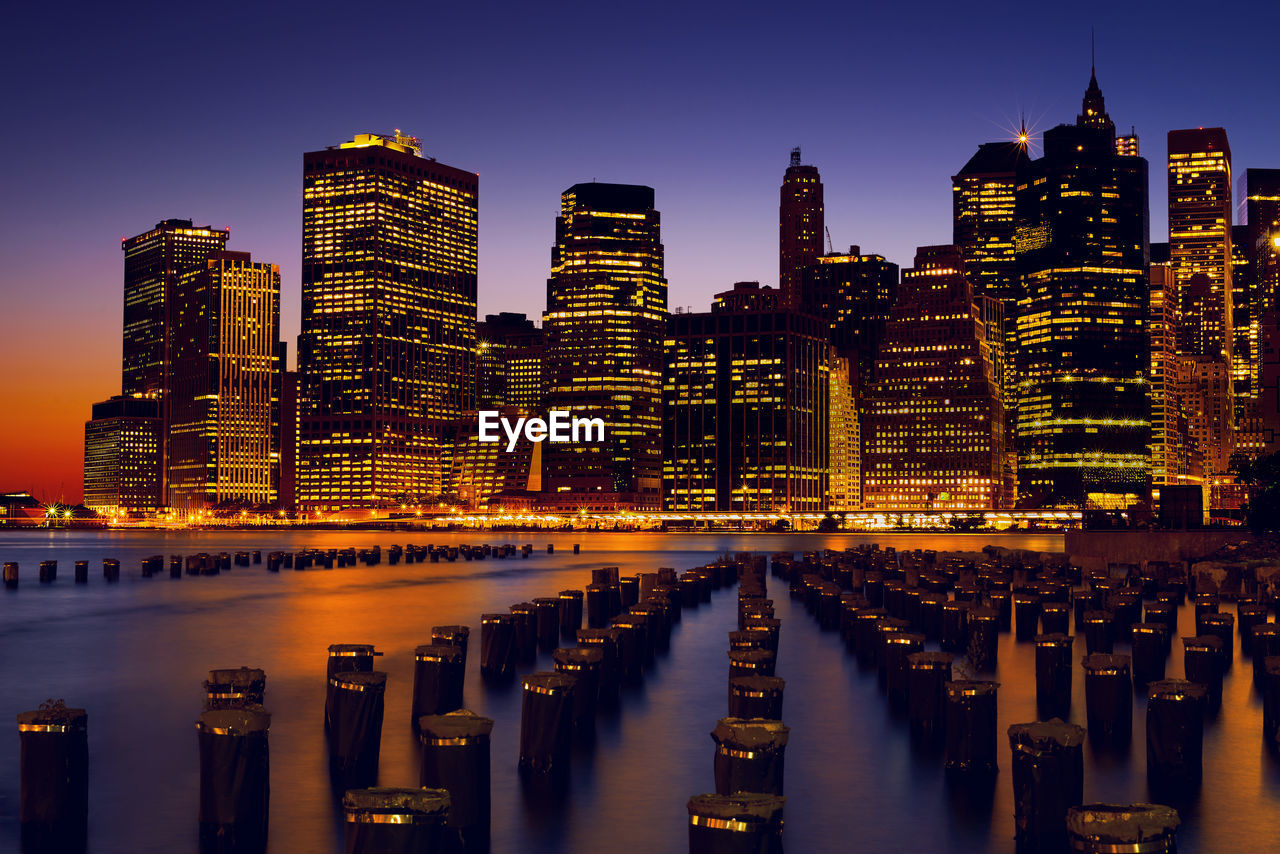 Illuminated modern buildings in city against sky at night