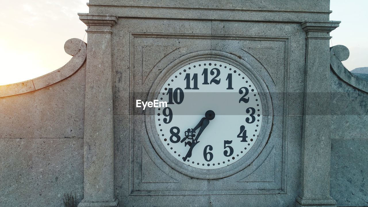 LOW ANGLE VIEW OF CLOCK ON WALL OF BUILDING