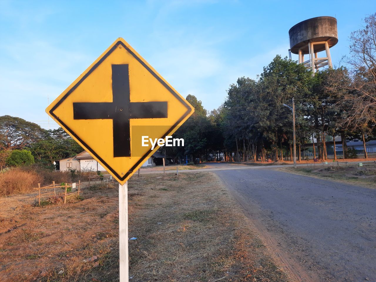 Road sign by trees against sky