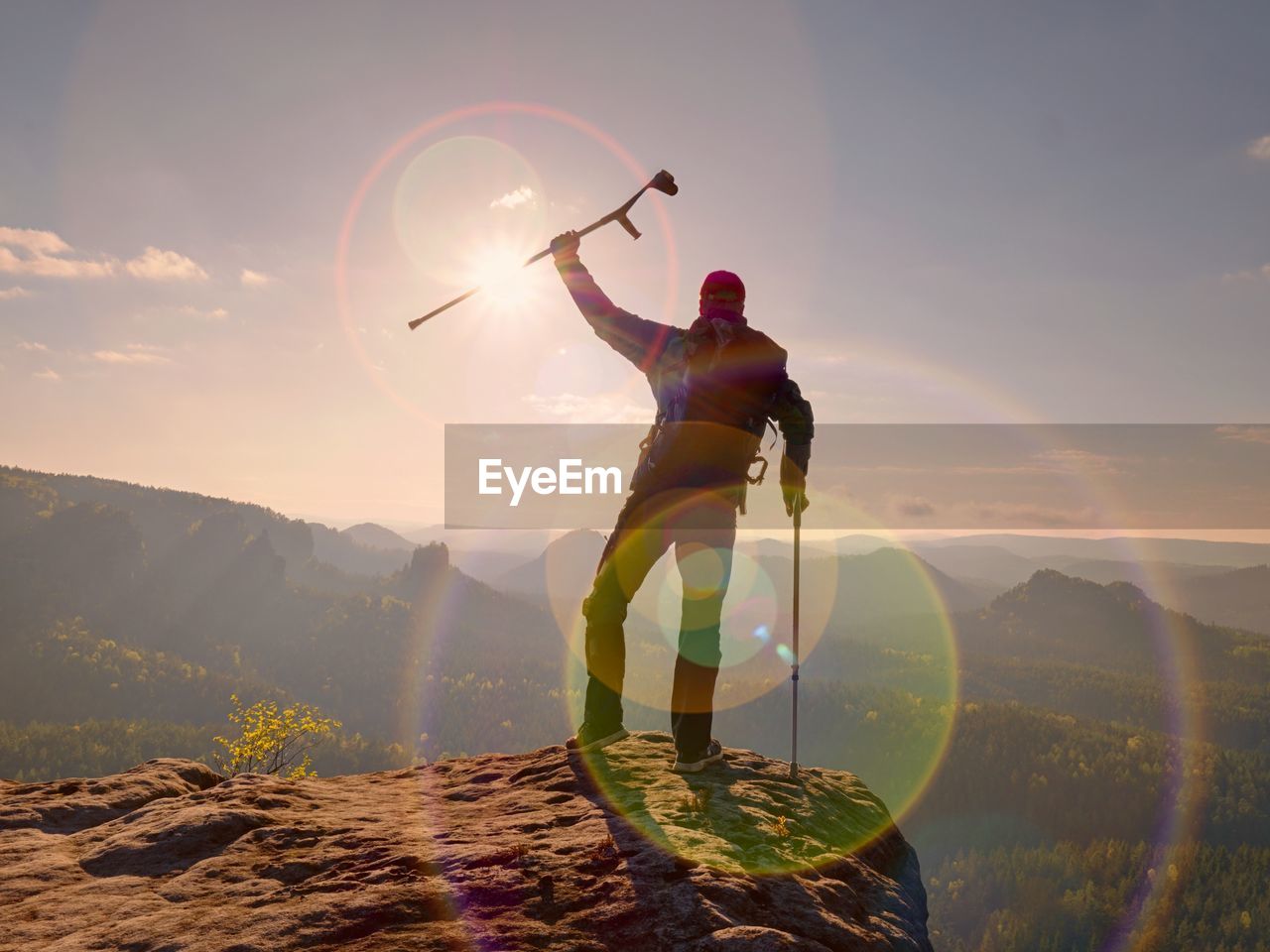 REAR VIEW OF MAN STANDING AGAINST MOUNTAIN RANGE