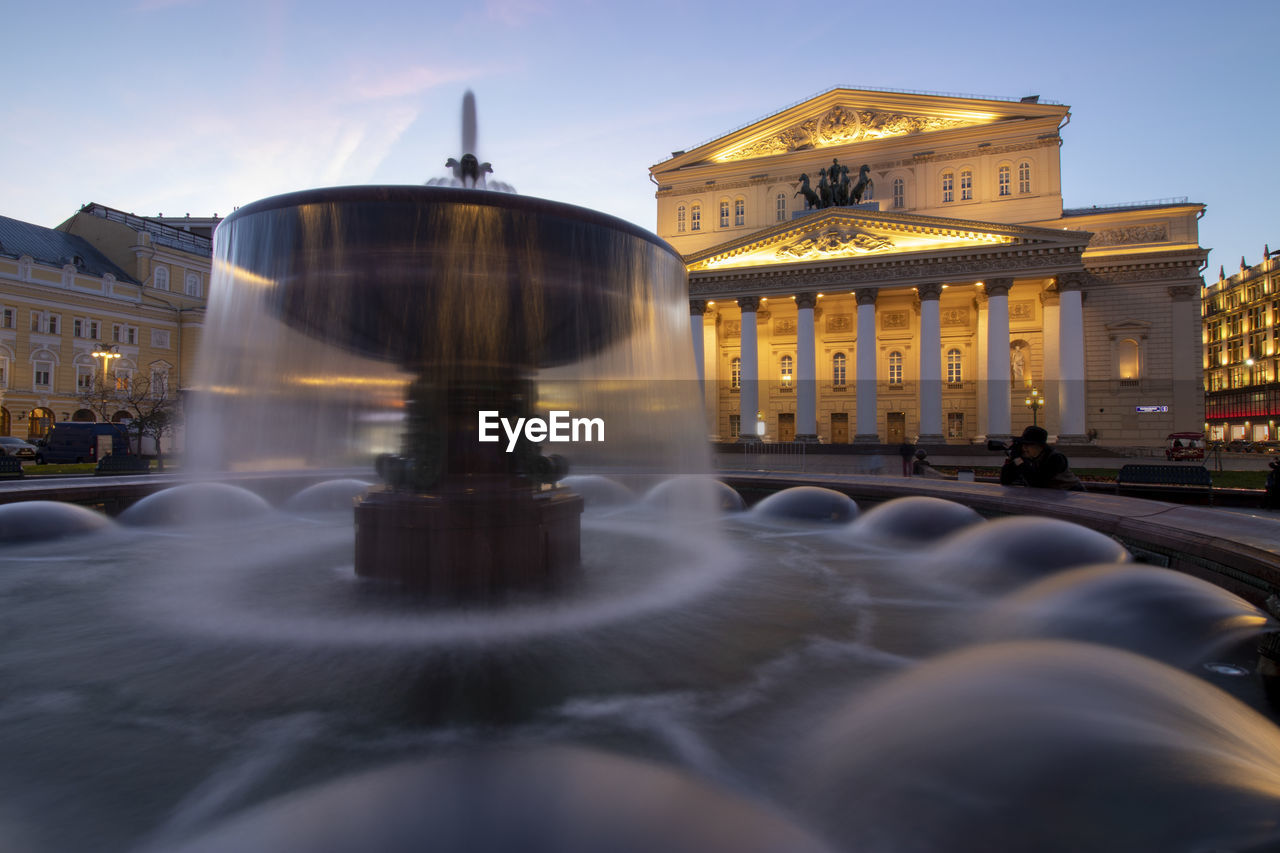 Fountain in city against sky