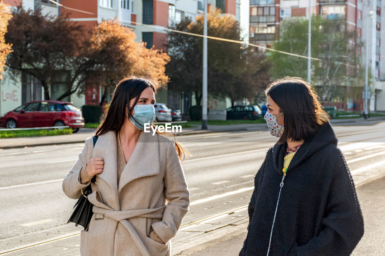 Two friends walking in city, wearing protective masks during corona virus epidemic, female, women.