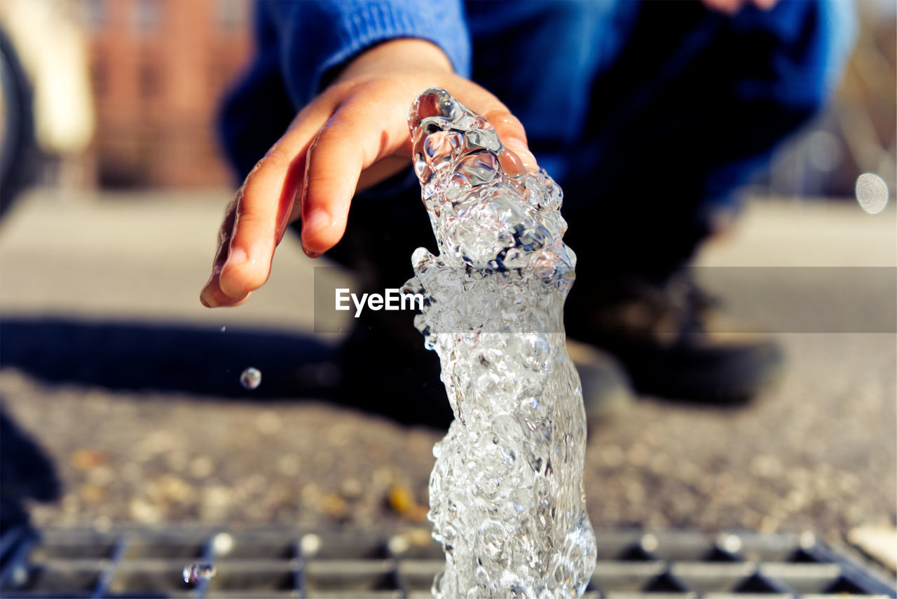 CLOSE-UP OF PERSON HOLDING FOUNTAIN
