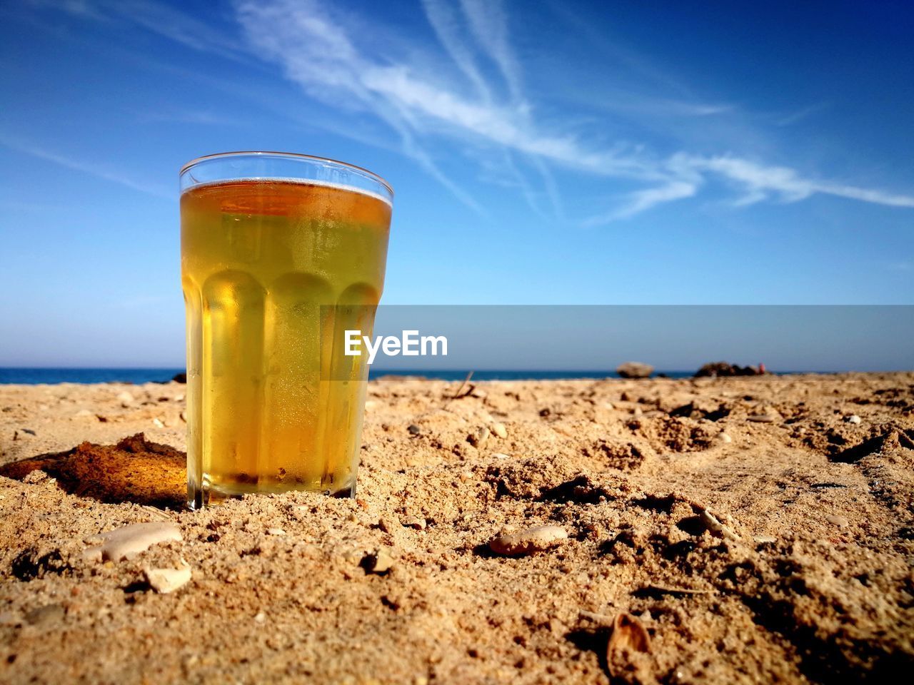 Close-up of beer on beach against clear blue sky