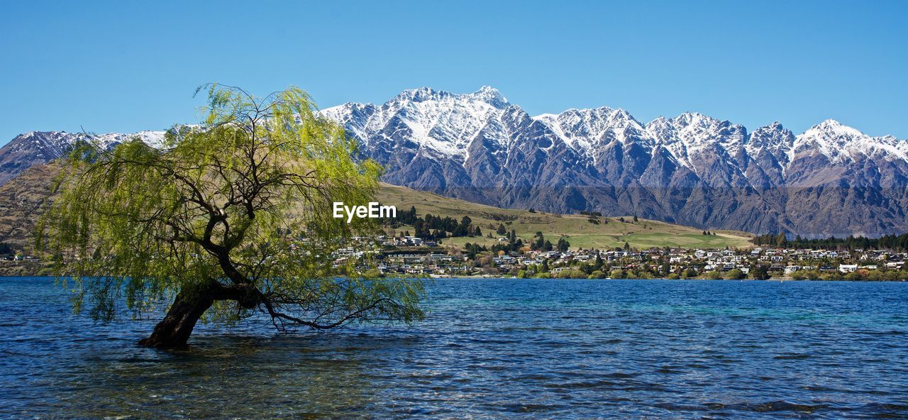 Scenic view of sea and mountains against clear blue sky