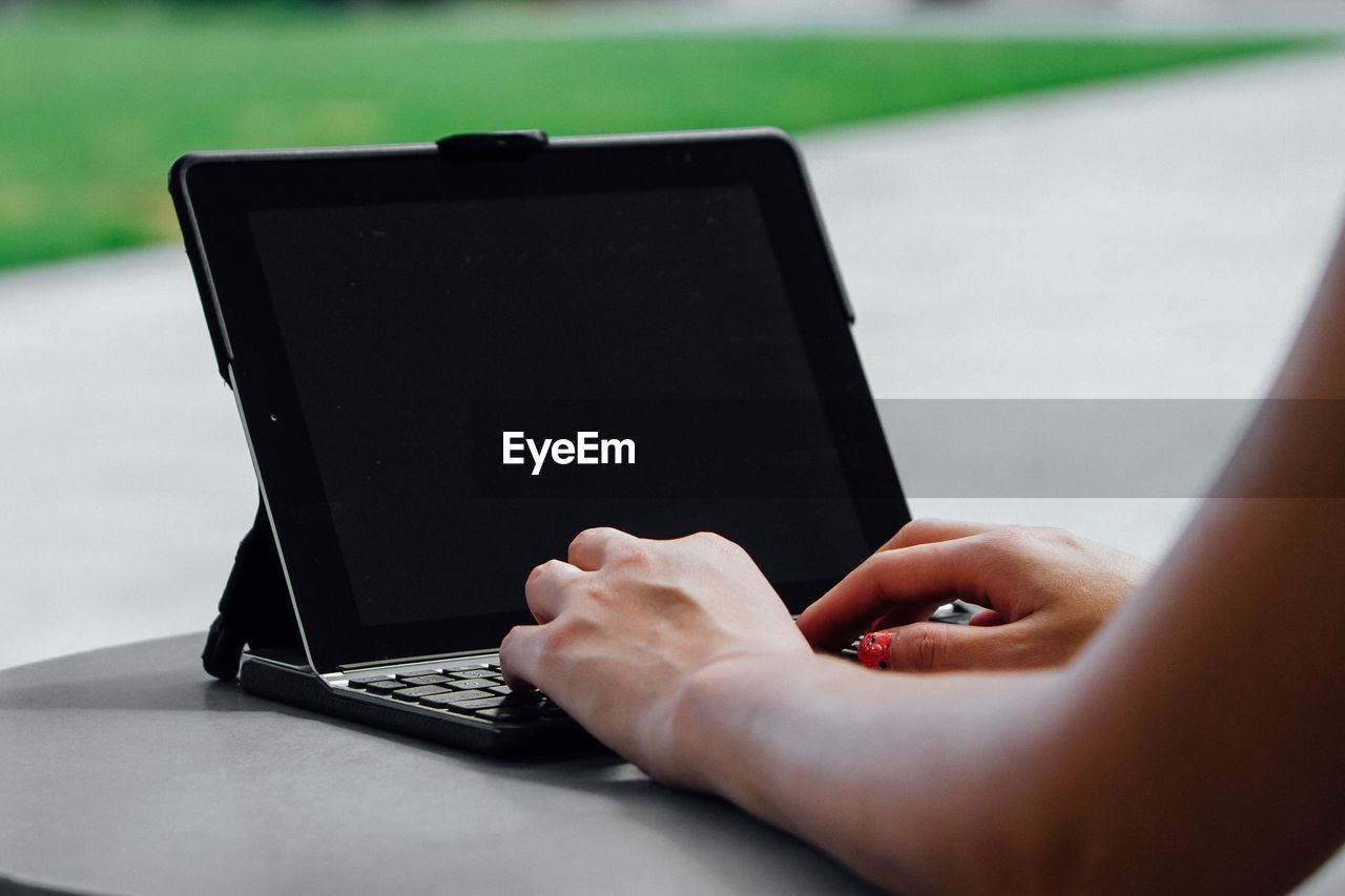 Cropped hand of woman using laptop