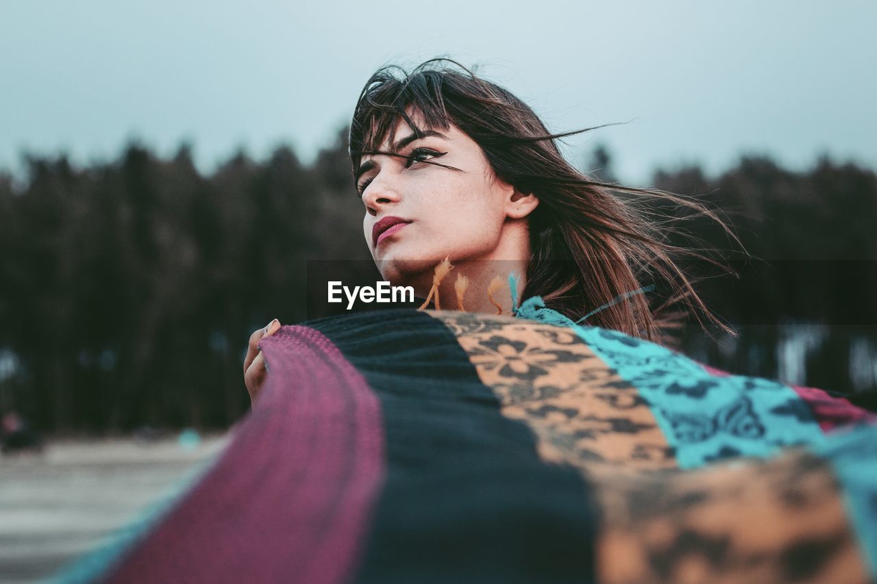 PORTRAIT OF WOMAN LOOKING AWAY OUTDOORS