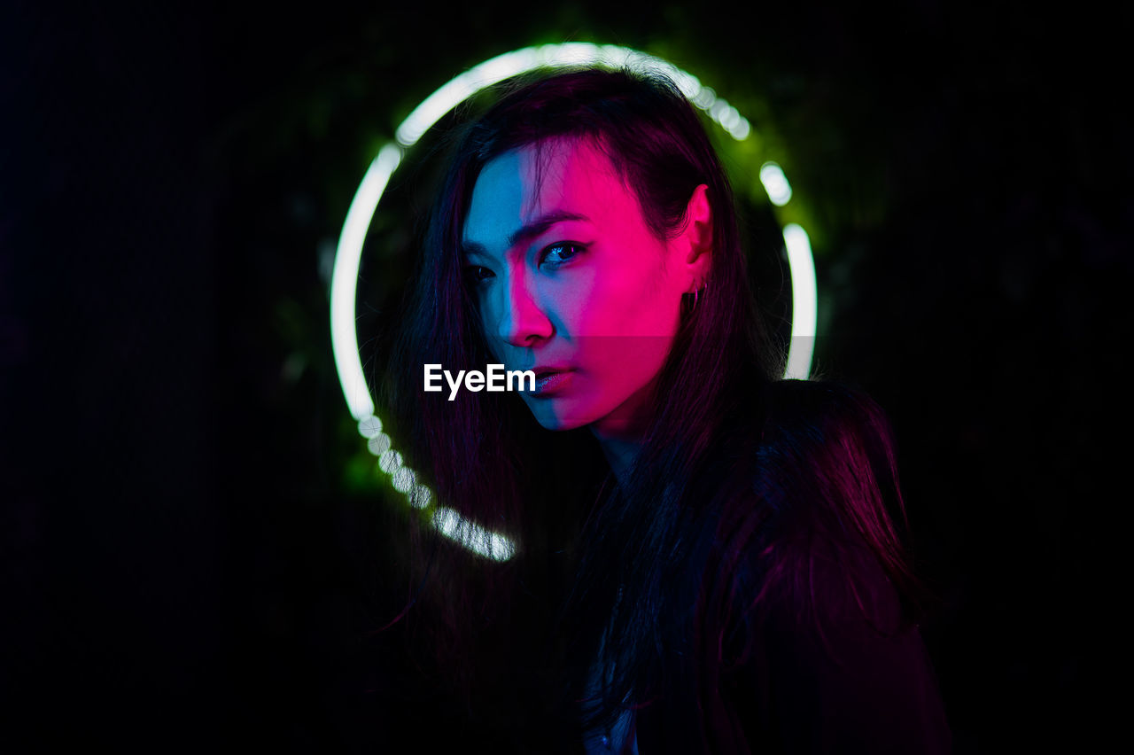 Portrait of young woman standing against lighting equipment