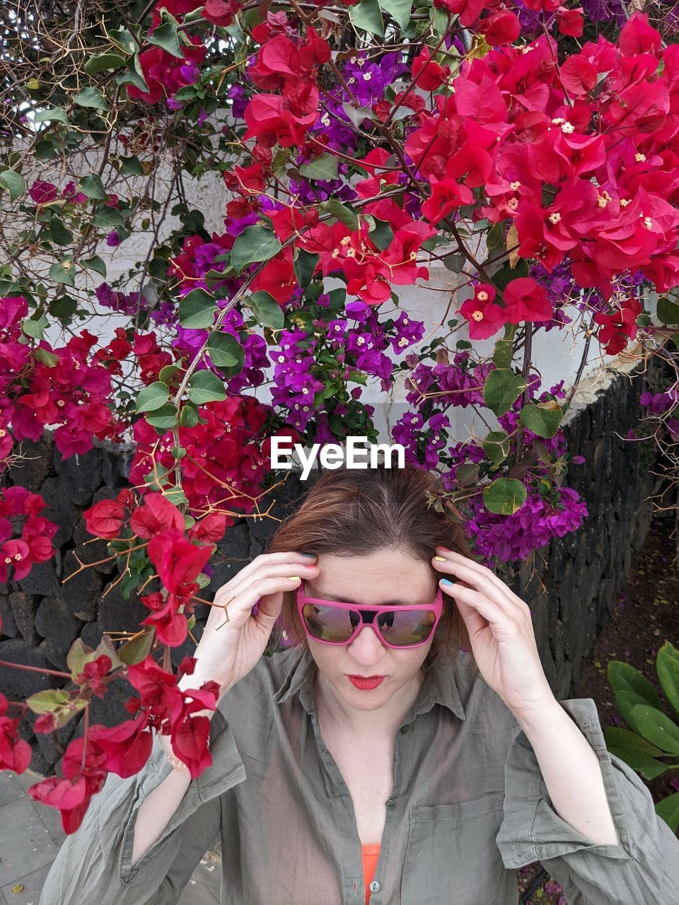 plant, one person, flower, spring, flowering plant, glasses, portrait, front view, women, nature, fashion, beauty in nature, pink, young adult, sunglasses, adult, looking at camera, leisure activity, lifestyles, outdoors, day, red, fragility, freshness, headshot, clothing, standing, female, growth, floristry, leaf, eyeglasses, hairstyle, waist up, smiling, plant part, autumn