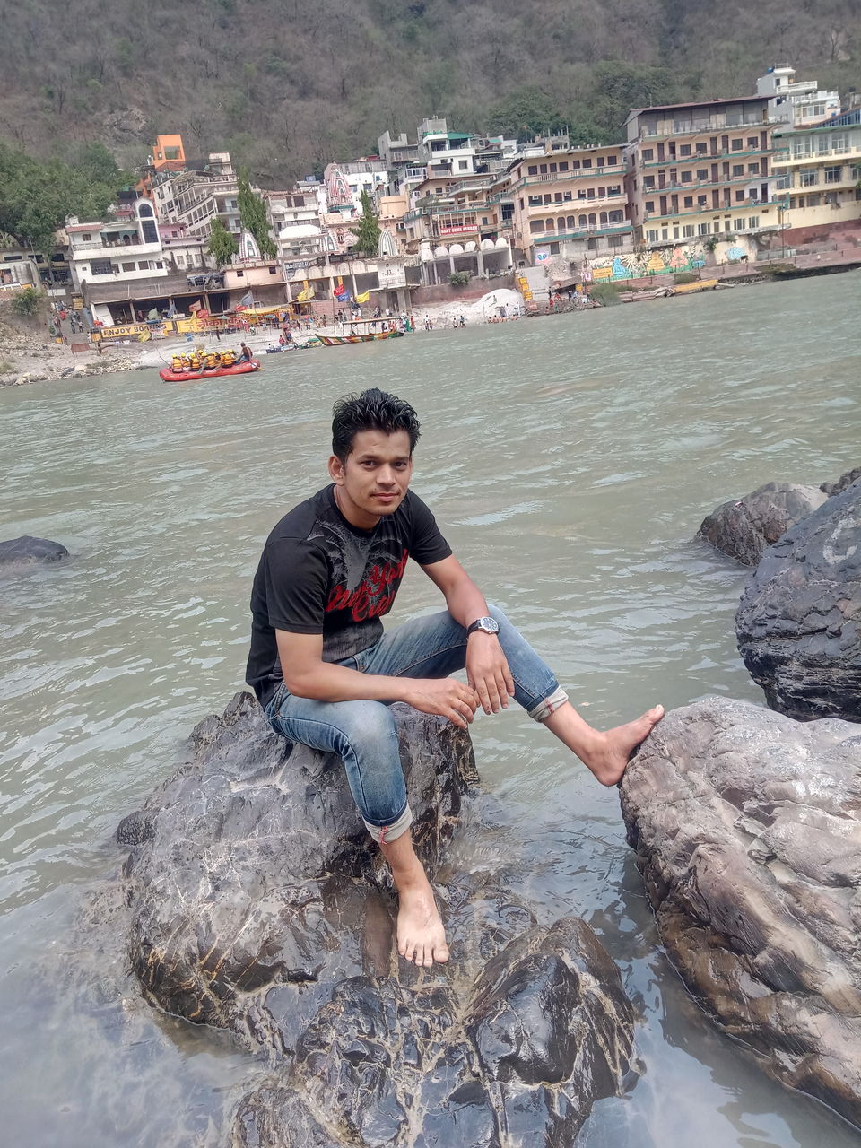 Portrait of man sitting on rock amidst sea in city