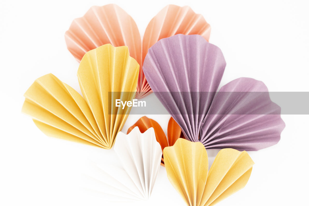 Purple, yellow, and orange colored paper hearts on white background