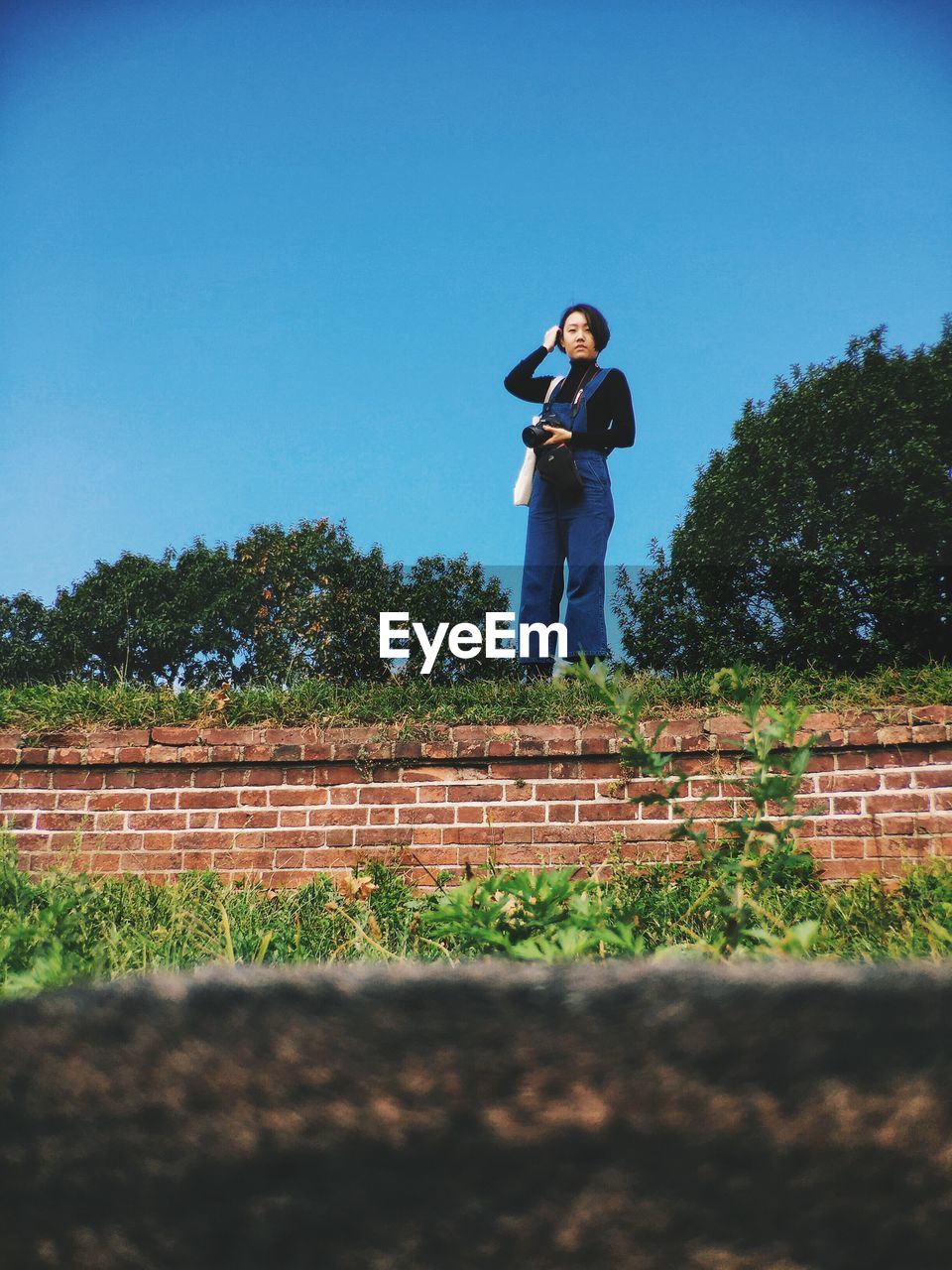 LOW ANGLE VIEW OF YOUNG WOMAN STANDING ON FIELD
