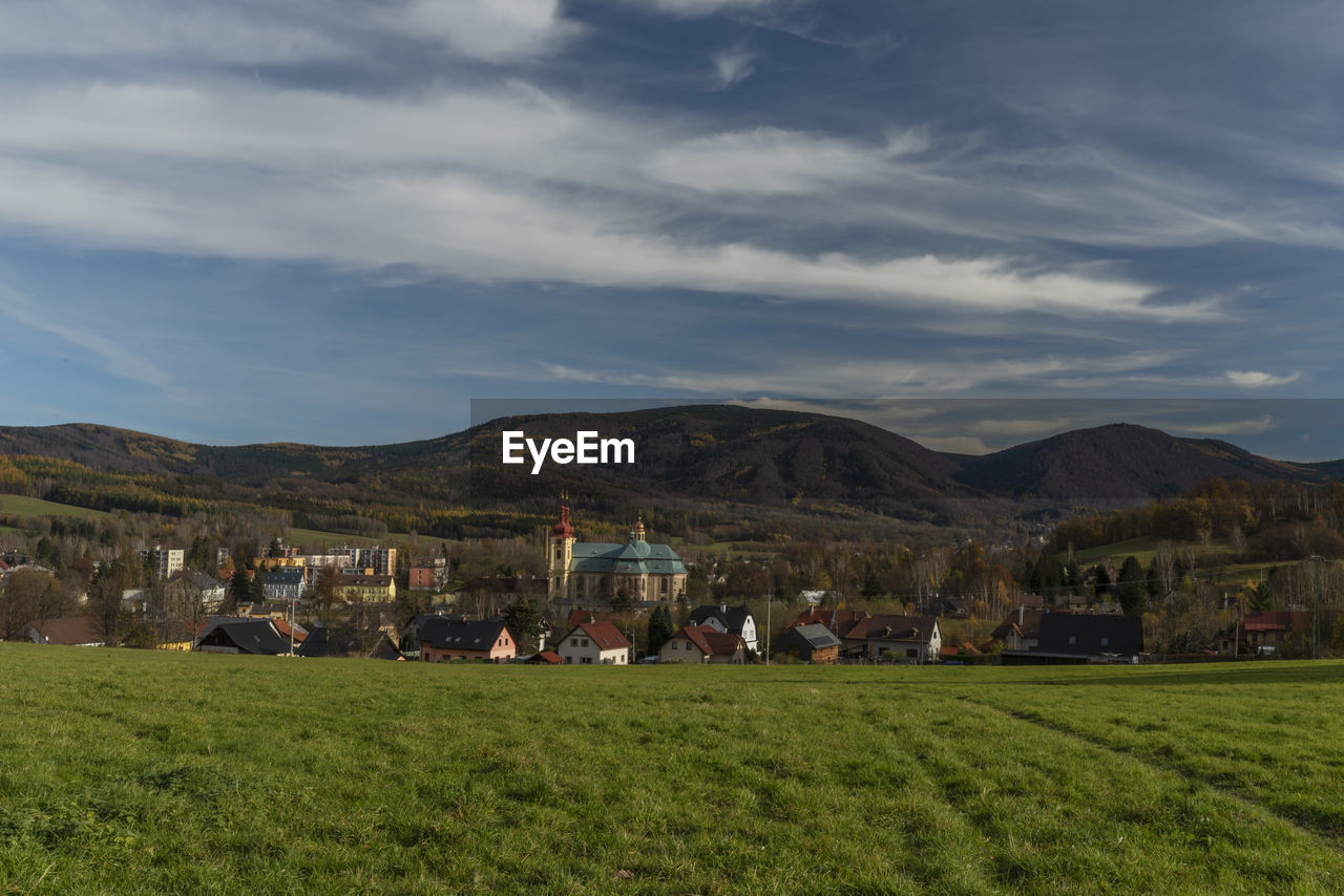 SCENIC VIEW OF FIELD AND BUILDINGS AGAINST SKY