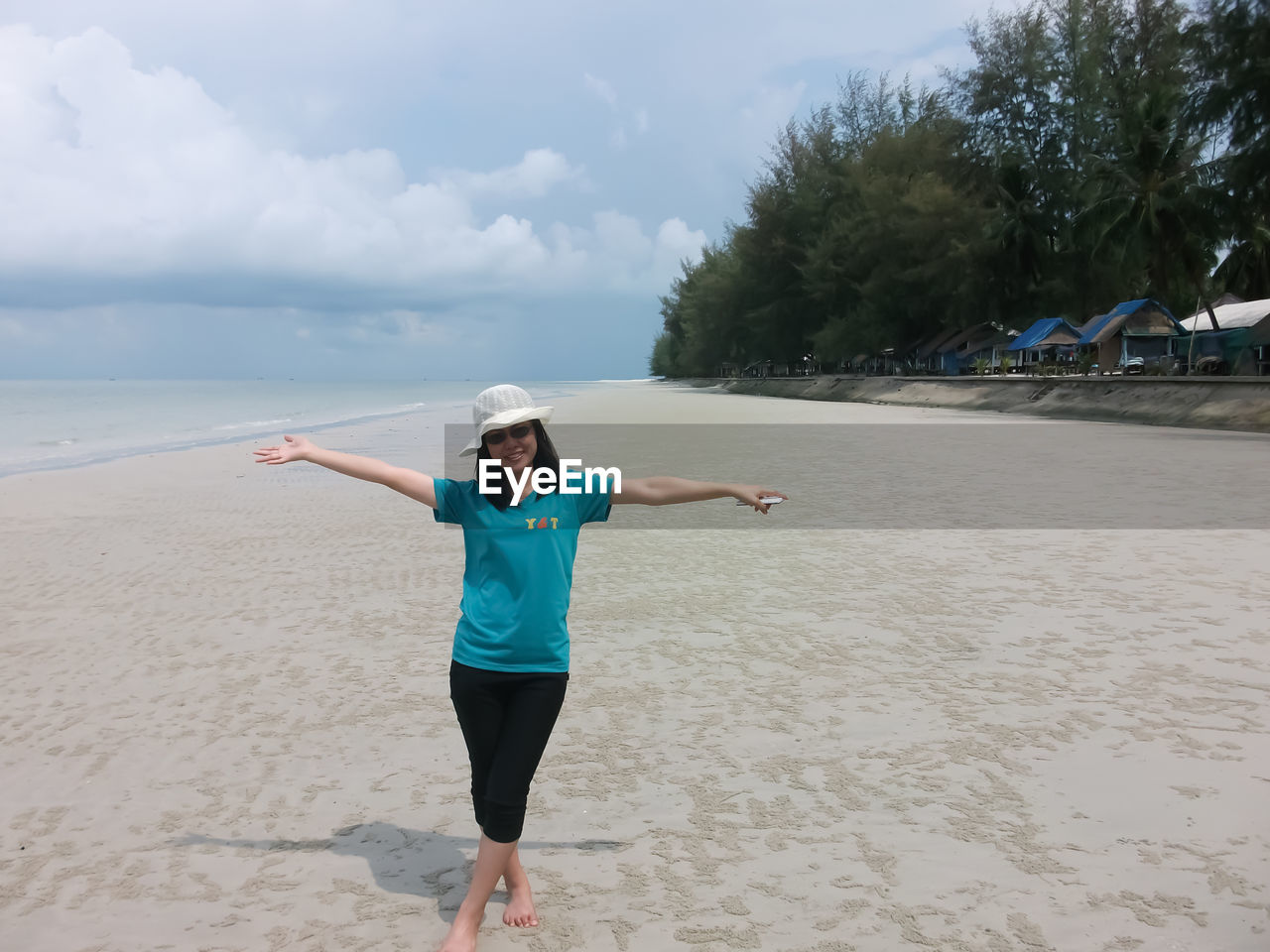 Portrait of woman with arms outstretched standing at beach