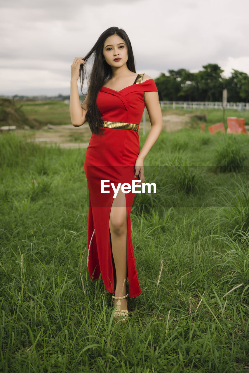 PORTRAIT OF WOMAN STANDING ON FIELD