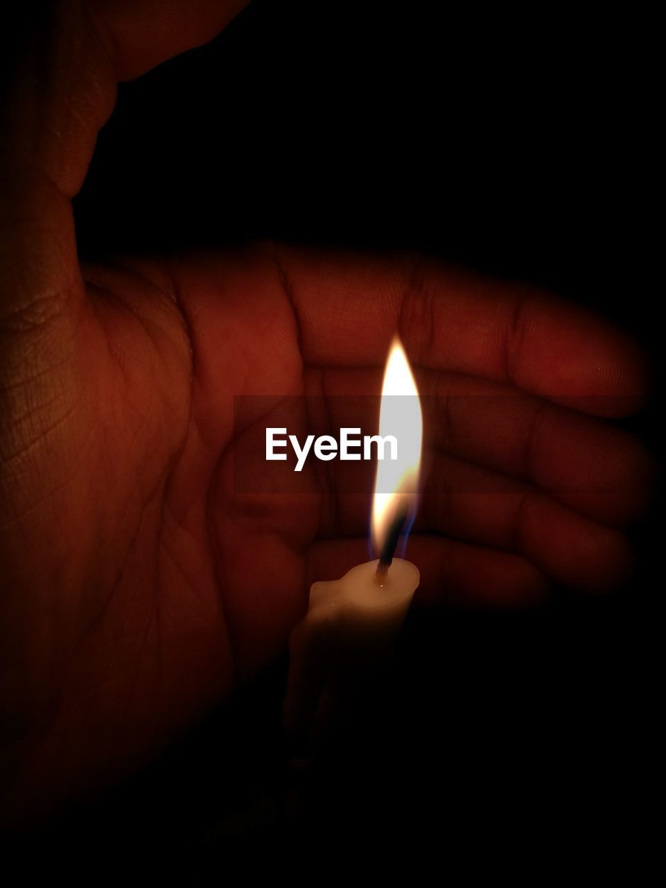 CLOSE-UP OF HUMAN HAND HOLDING ILLUMINATED LIGHT