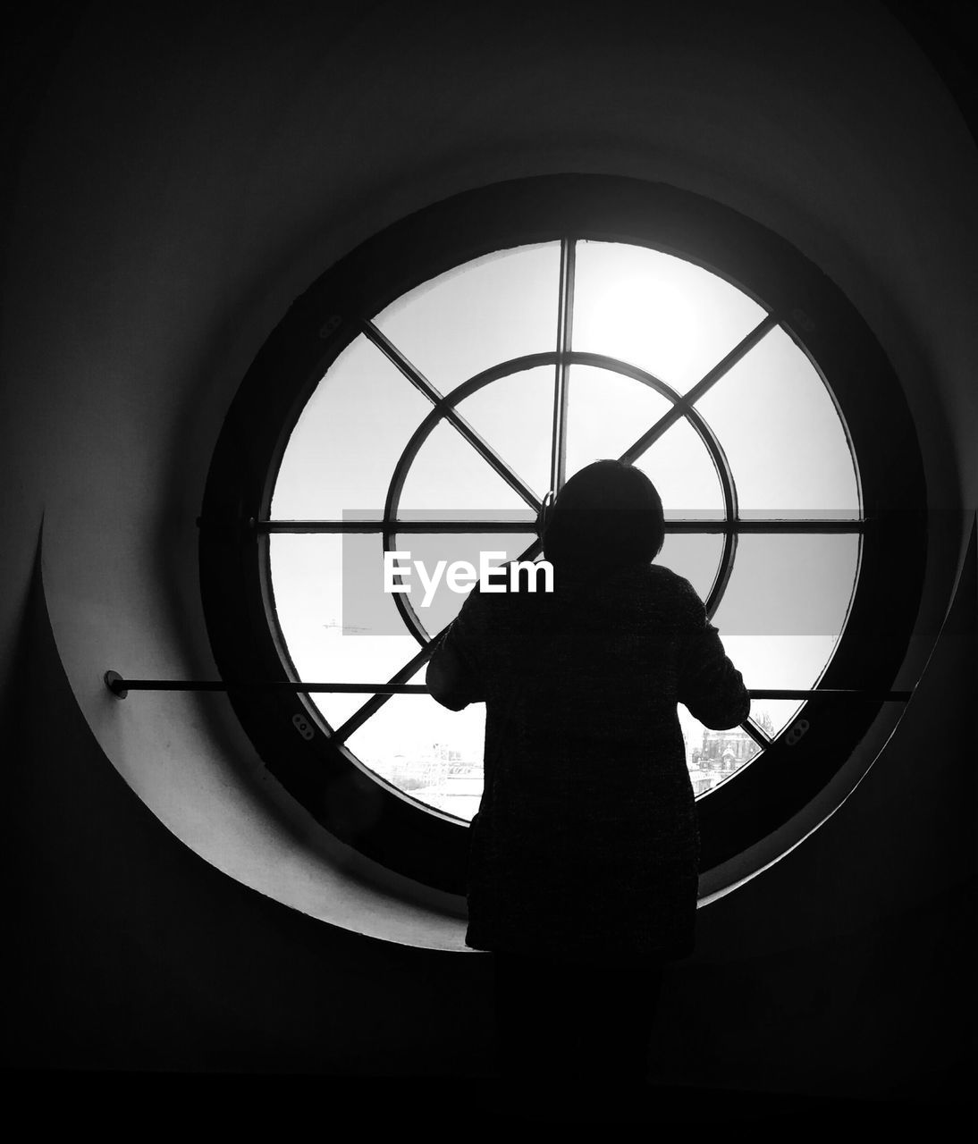 Rear view of person looking through window against sky