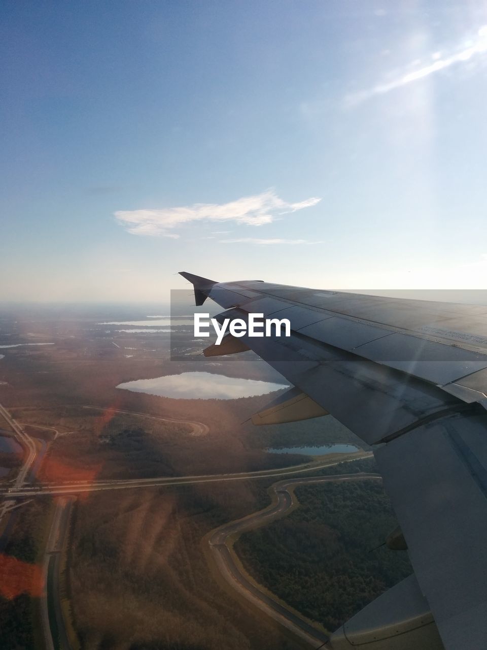 CROPPED IMAGE OF AIRPLANE WING OVER LANDSCAPE