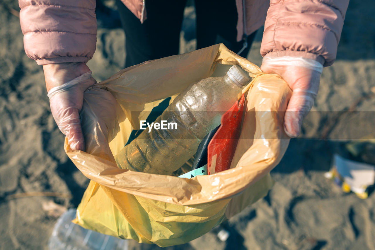 Midsection of woman showing plastic with garbage