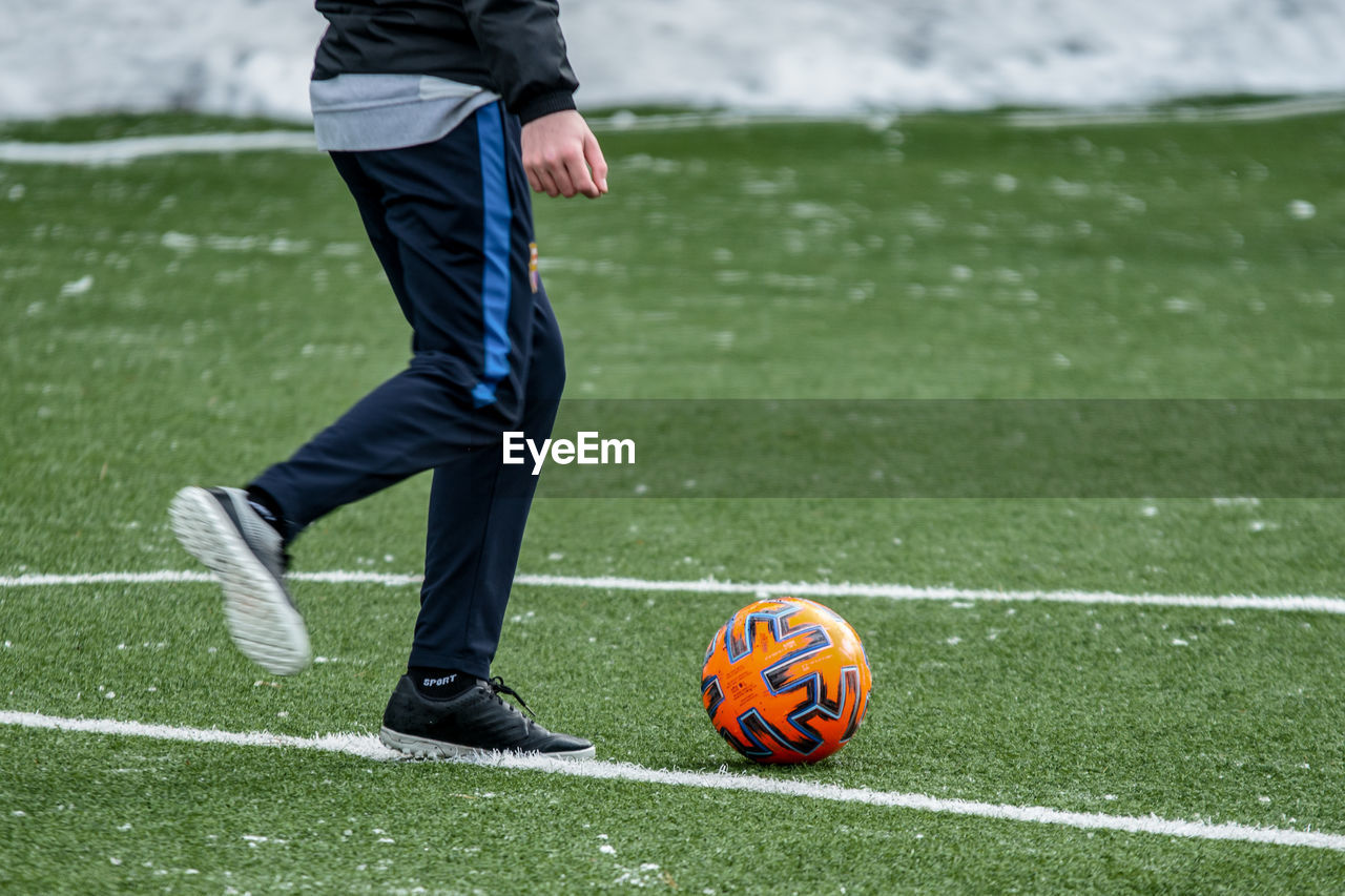 Low section of man playing soccer ball on grass