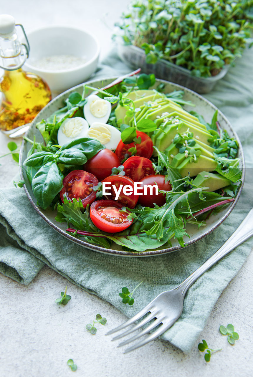 Fresh summer salad with arugula, red cherry tomatoes, basil, eggs and avocado. vegan food. 