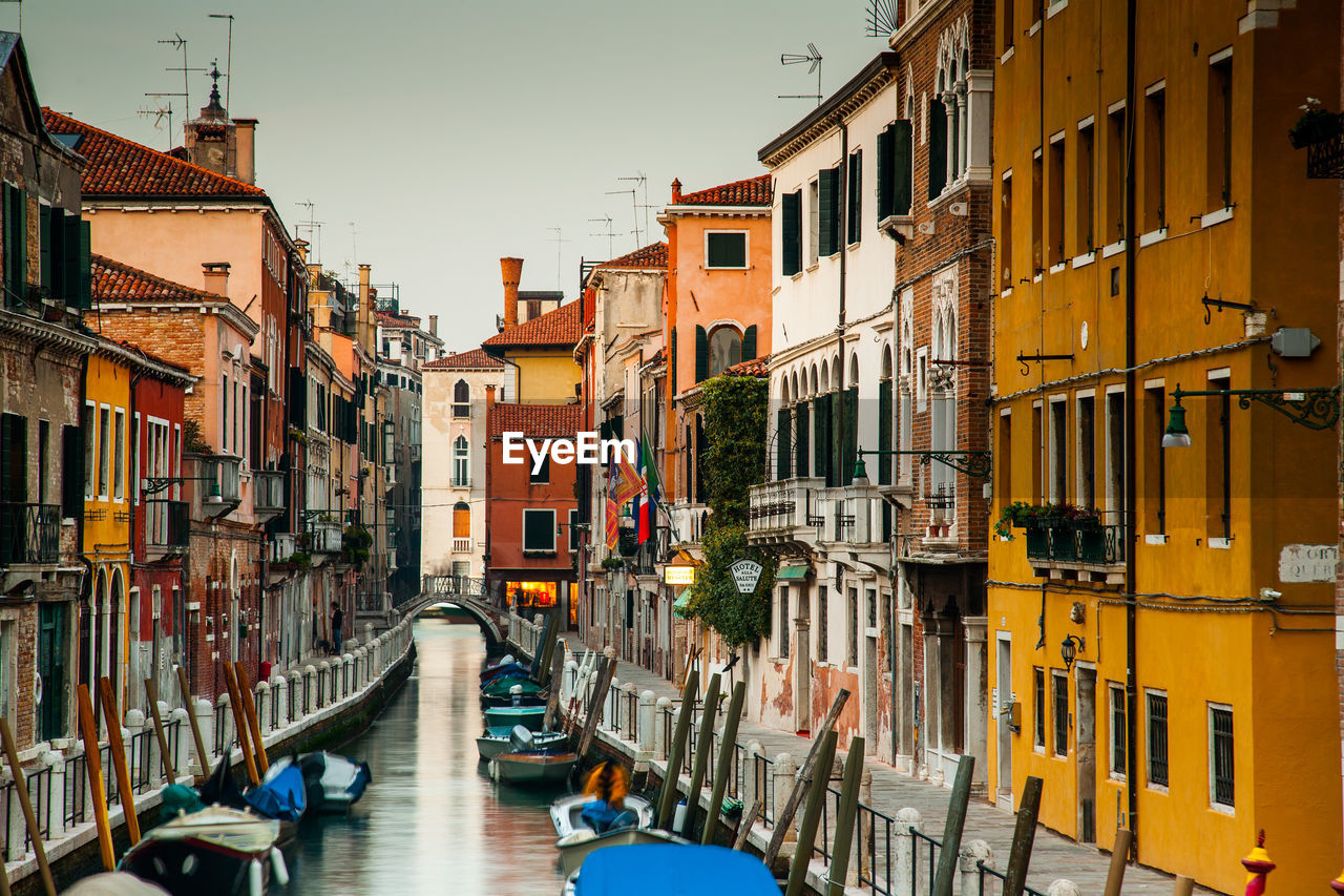 Canal amidst buildings in city against sky