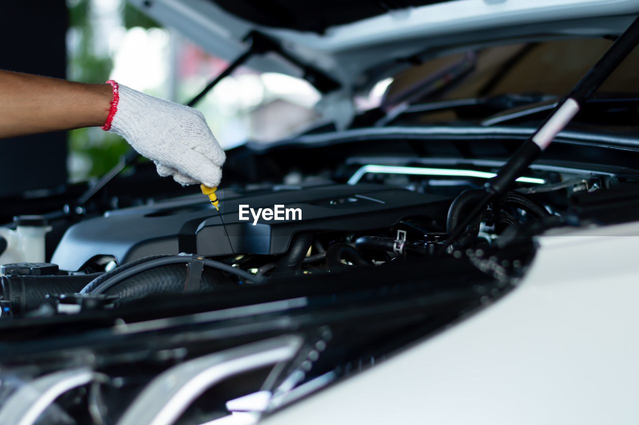 Close up of a car mechanic checking the oil level in a mechanical workshop.