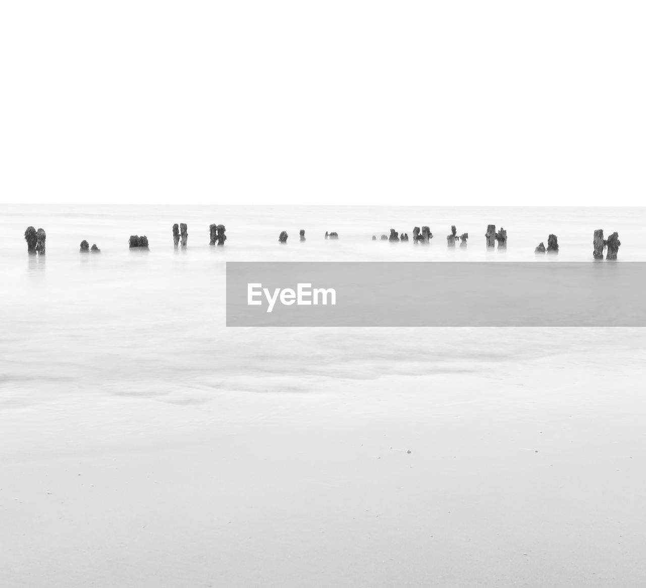 Wooden posts in sea against clear sky