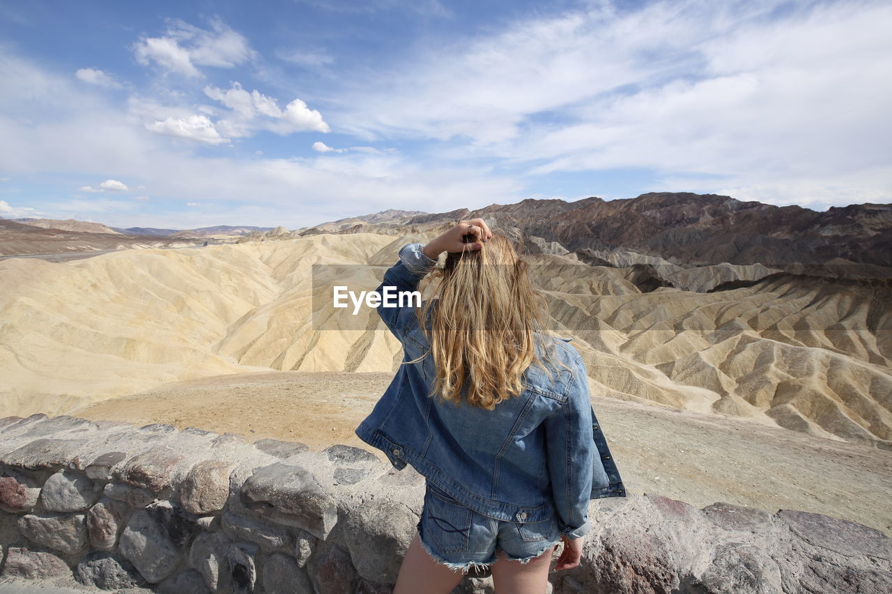 Rear view of woman with hand in hair standing at desert