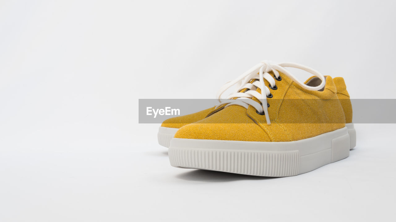 CLOSE-UP OF YELLOW SHOES ON WHITE BACKGROUND
