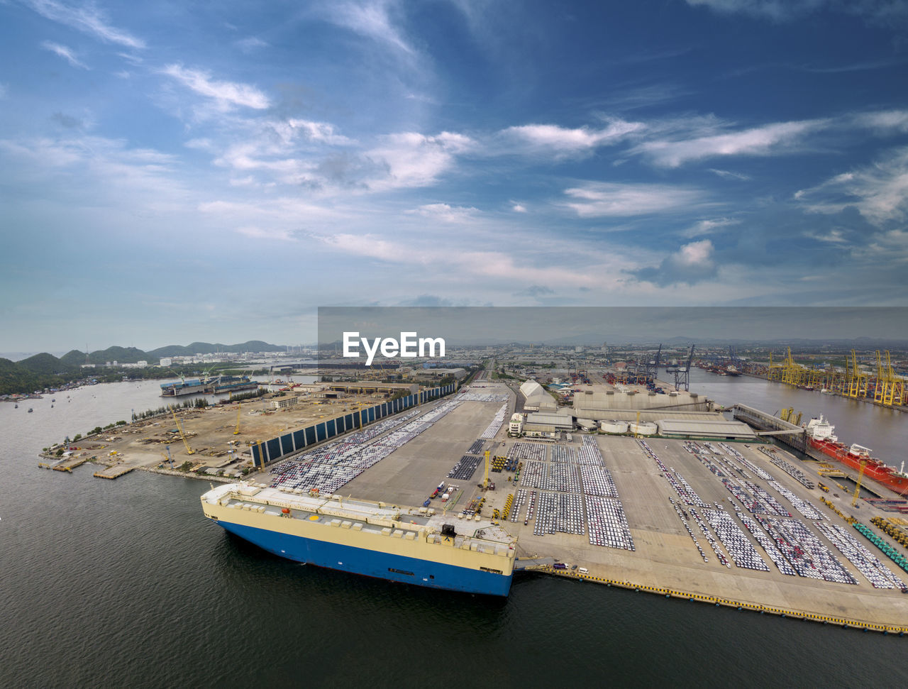 Aerial logistics commercial vehicles waiting to be load on to a car carrier ship at dockyard