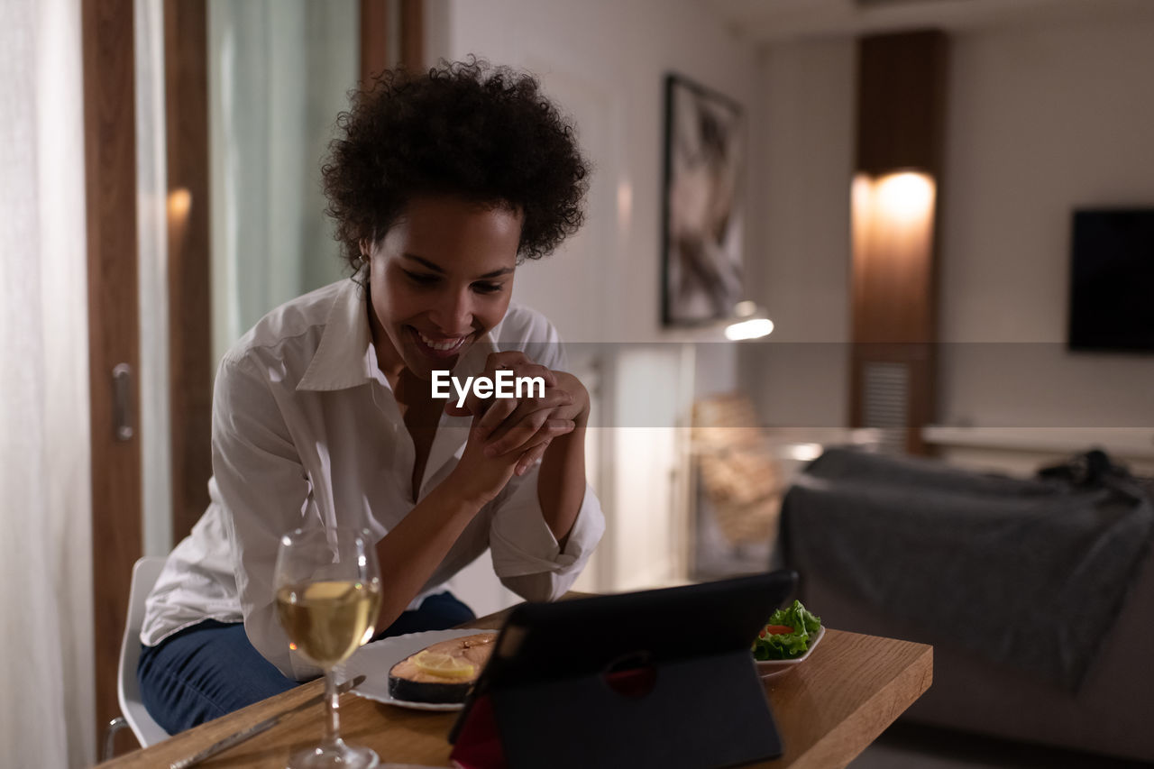 Happy ethnic woman having online date during dinner