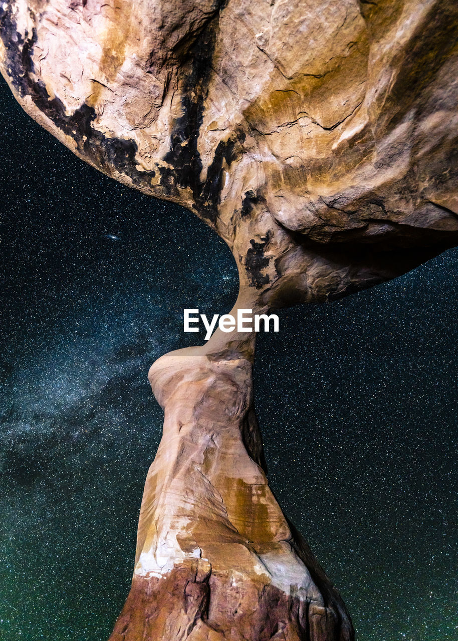 Low angle view of rock formations against star field