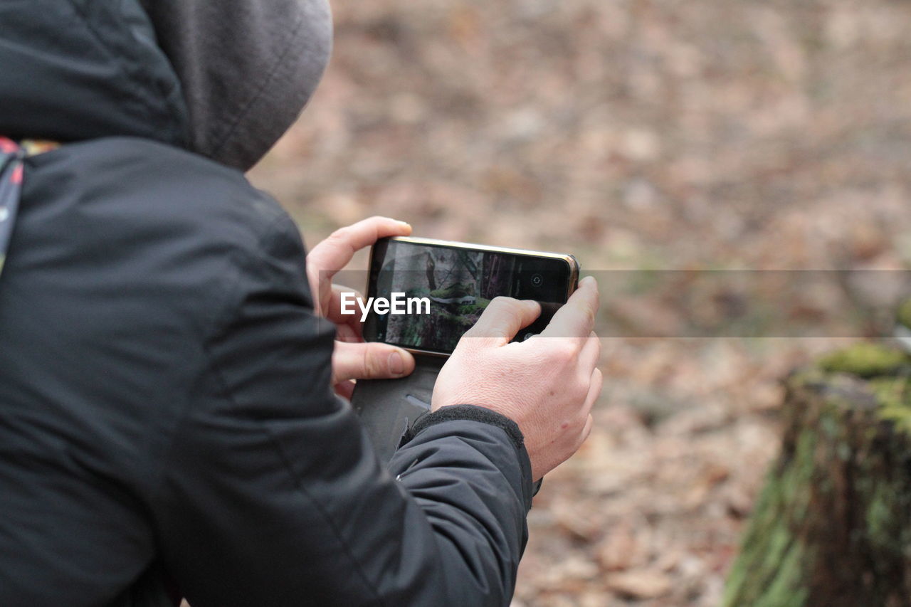 Midsection of man photographing with mobile phone