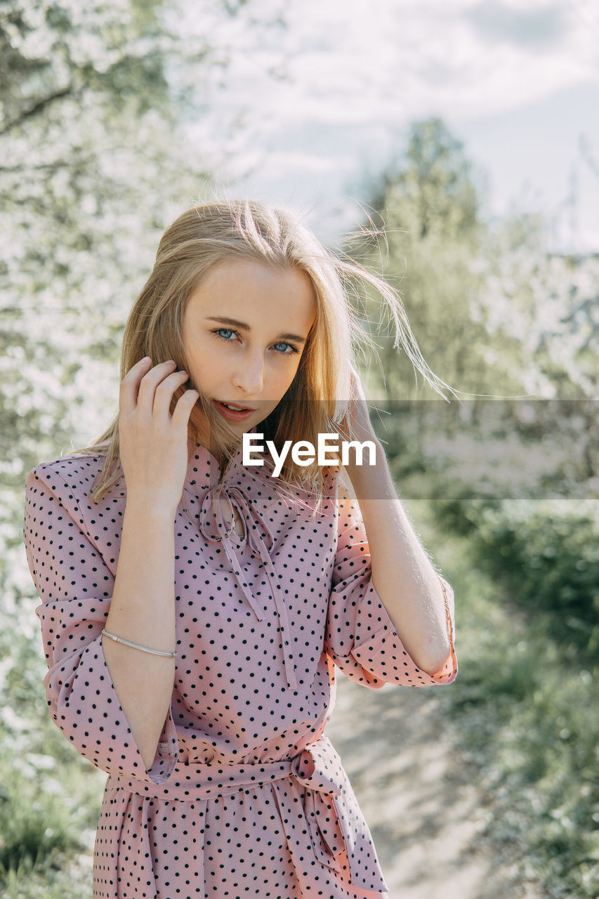 Portrait of young woman standing against trees