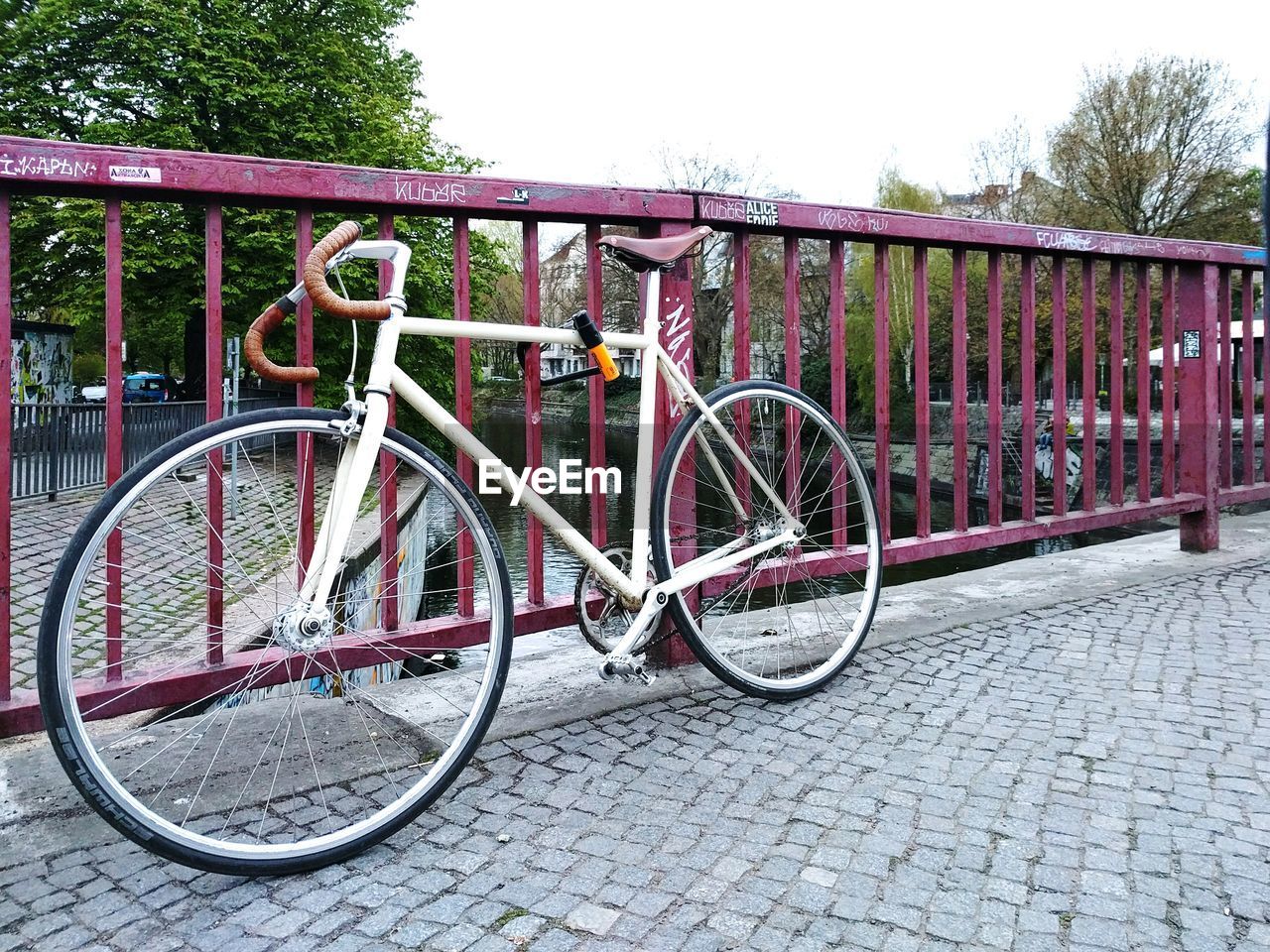 Bicycle parked on bridge over canal against clear sky