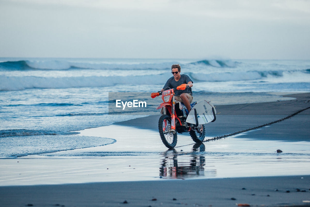 PEOPLE RIDING BICYCLE ON BEACH