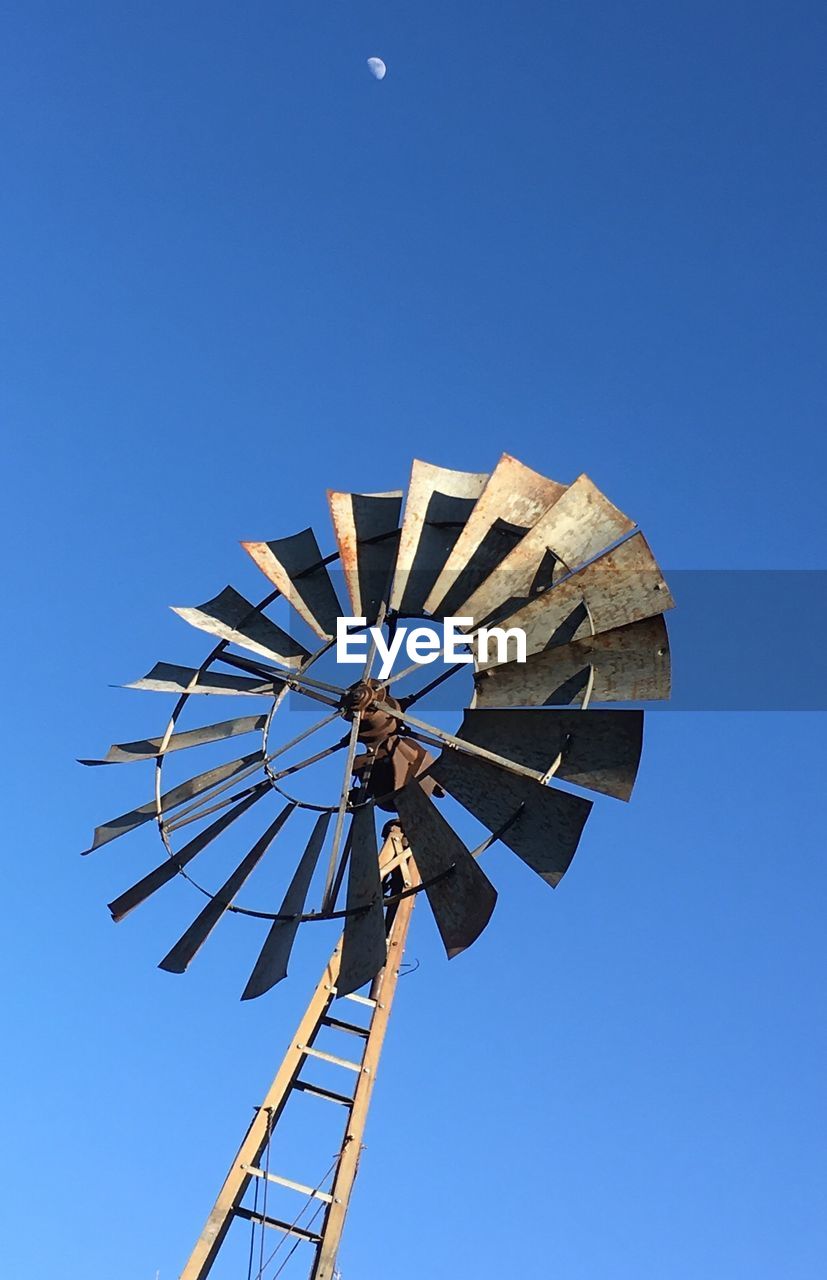 Windmill and lunar ghost against a clear blue sky