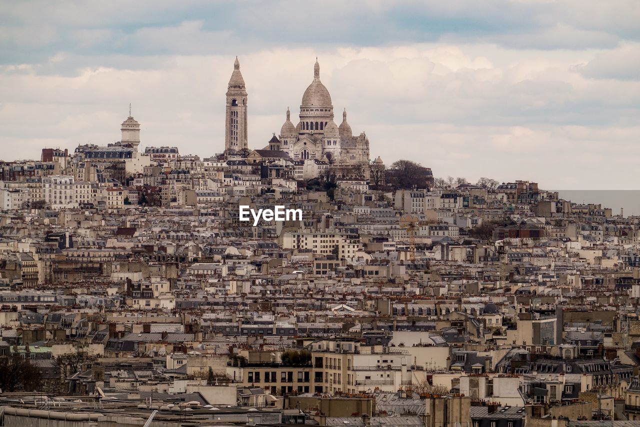 View of buildings in town against cloudy sky