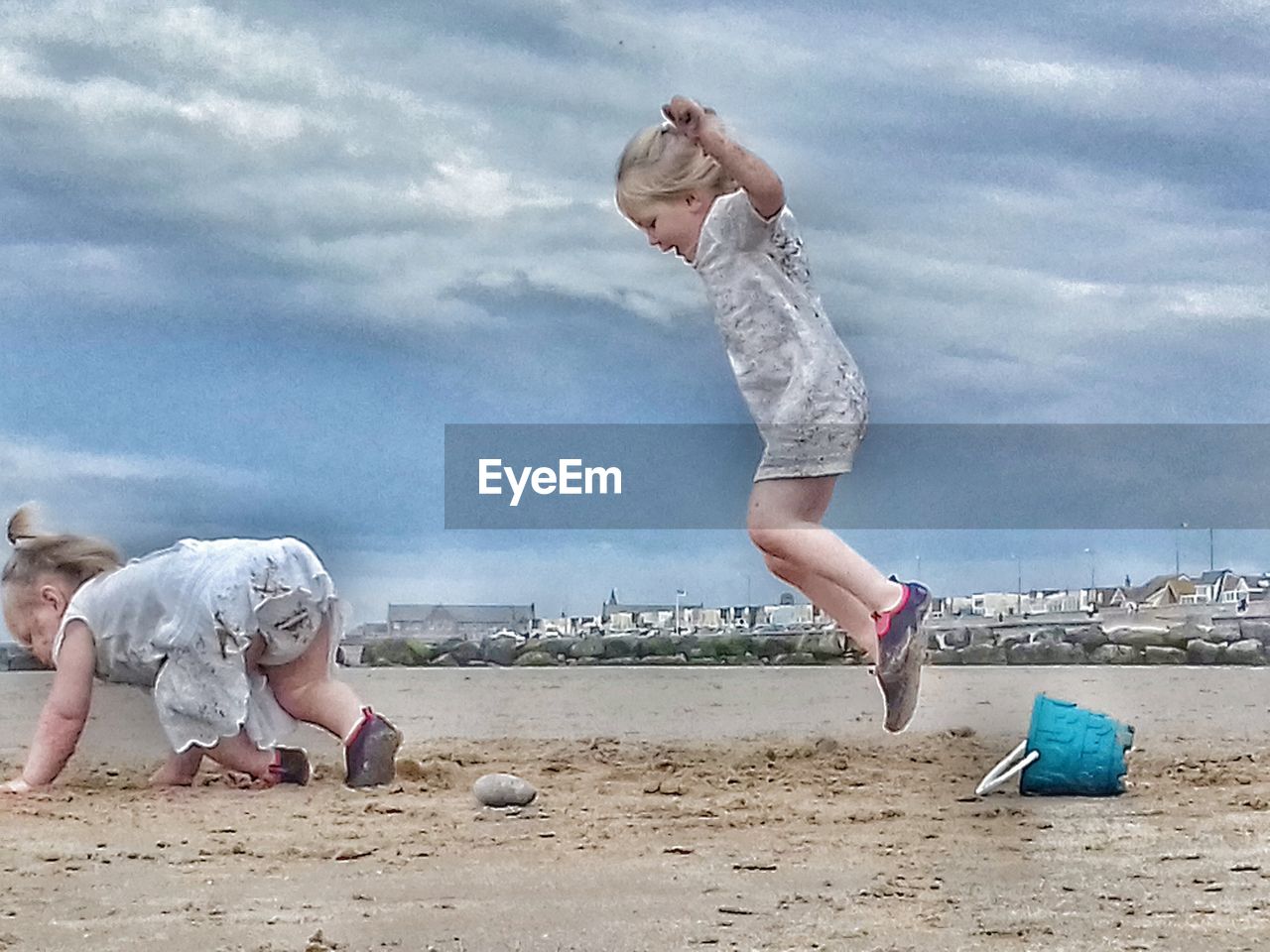 CHILDREN PLAYING ON SAND AGAINST SKY